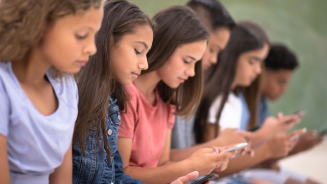 Imagen de adolescentes concentrados en sus teléfonos, evidenciando cómo la era digital domina las interacciones juveniles
